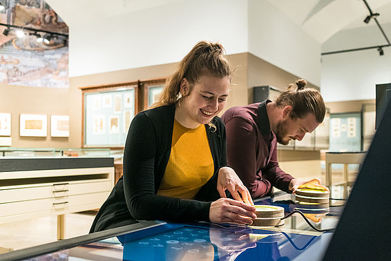 Eine Frau und ein Mann betrachten eine Vitrine im Papyrusmuseum