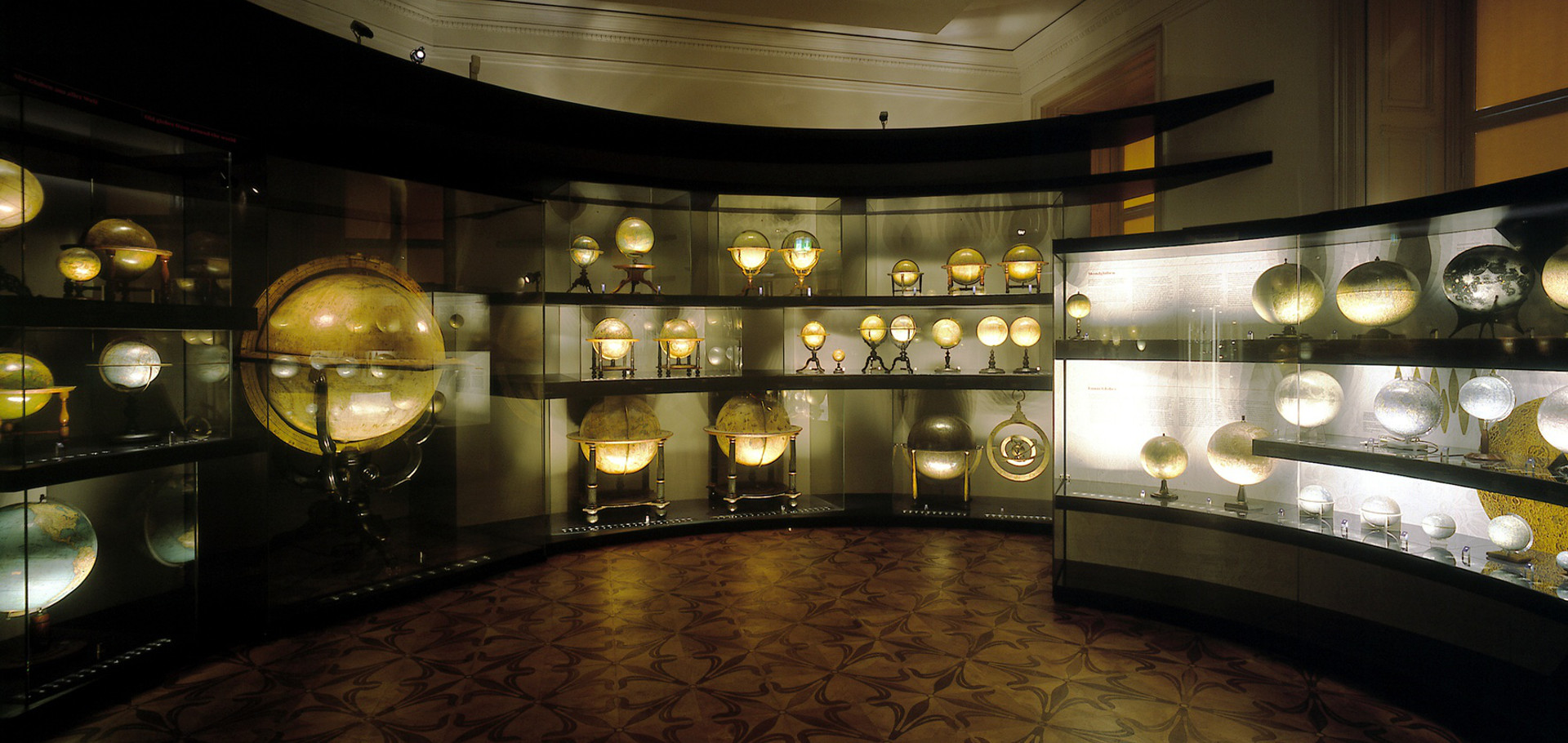 Dunkler Raum mit beleuchteten Globen in Vitrinen