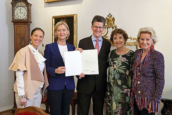 Vier Frauen und ein Mann posieren nebeneinander, die zwei mittig halten eine Urkunde