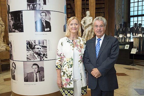 Blonde Frau mit Blumenblazer und grauhaariger Mann im Anzug