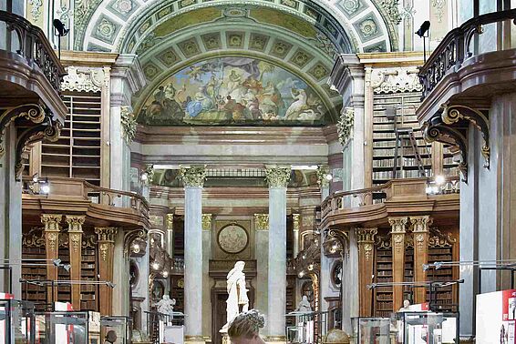 Frau in weißem Kleid in einem Marmorsaal mit Deckenfresko