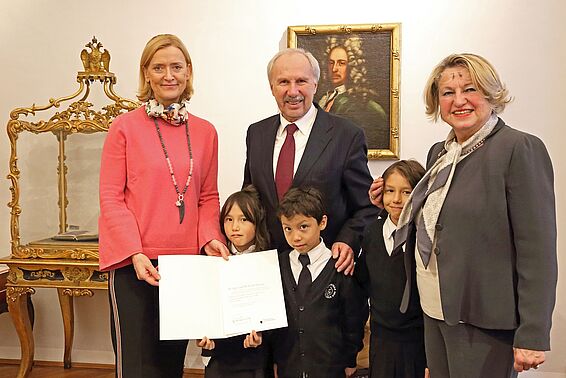 Zwei Frauen, ein Mann und drei Kinder posieren mit Urkunde