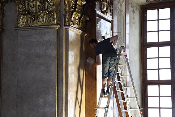 Arbeiter auf der Leiter putzt die Holzwand.