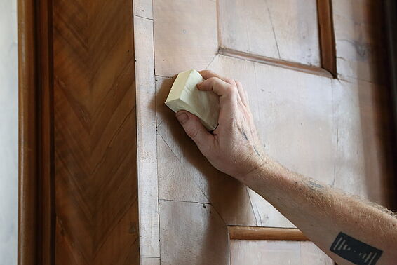 Person schleift das Holz auf der Wand.