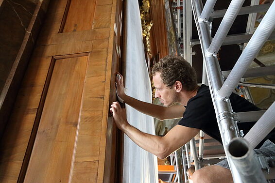Nahaufnahme vom Arbeiter wie er die Holzwand schleift.