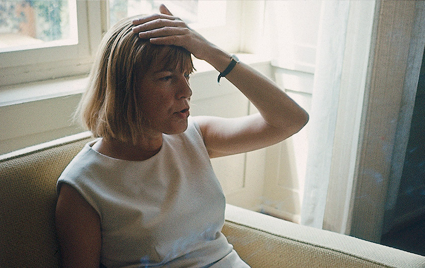 Foto von sitzender Frau, die sich an den Kopf greift