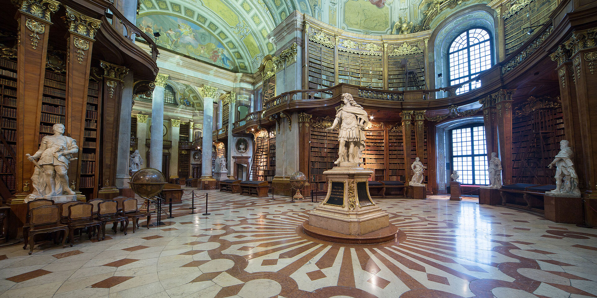 Foto von einem barocken Marmorsaal mit Bücherregalen und Statuen