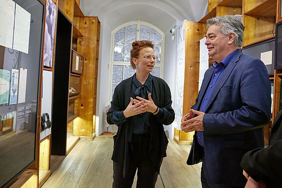 Eine Frau und ein Mann unterhalten sich zwischen Museumsregalen.