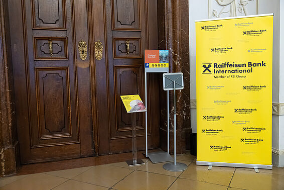 Foto von Holztür mit Ständer mit Logos der Raiffeisenbank