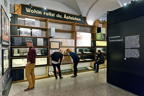 Verschiedene Menschen in Museumsraum mit Bücherregalen