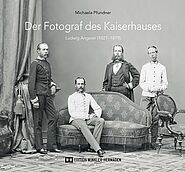 Drei Männer und ein junger Mann in Uniformen aus der Kaiserzeit sind um ein Sofa positioniert. Titel: Der Fotograf des Kaiserhauses