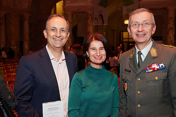 1 Mann im Anzug, 1 Frau in grünem Kleid und 1 Mann in Militär-Uniform