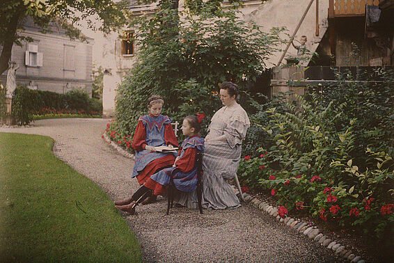 Zwei Mädchen und eine Frau sitzen in einem Garten
