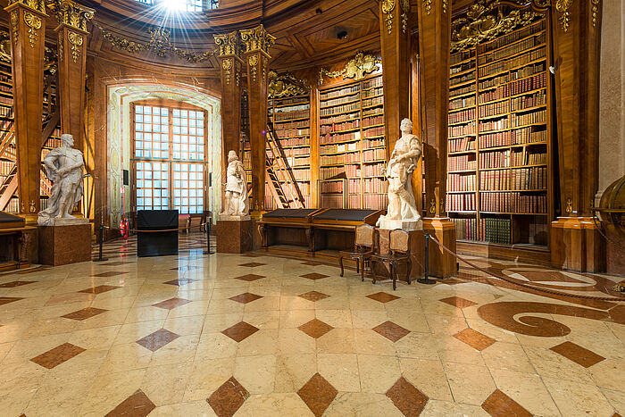 Foto von Marmorsaal mit Statuen und Bücherregalen.