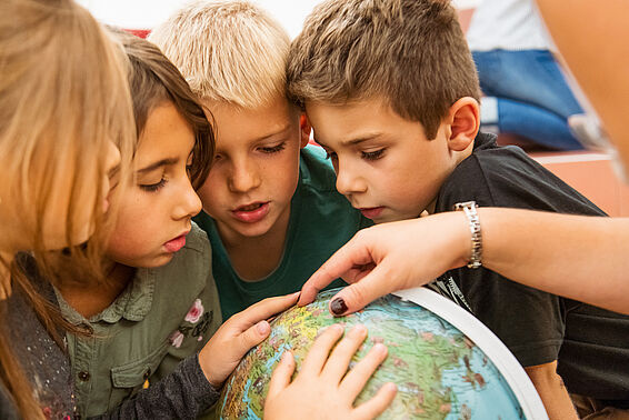 Kinder betrachten einen Globus im Globenmuseum