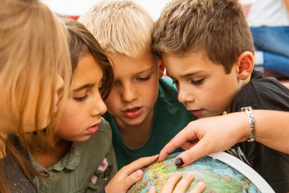 Vier Kinder betrachten einen Globus