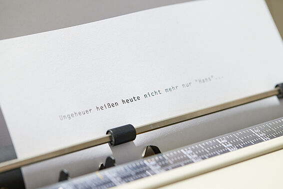 Foto von Zettel in einer Schreibmaschine, darauf steht "Ungeheuer heißen heute nicht mehr nur Hans..."