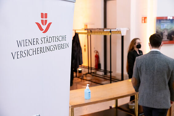 Garderobe, daneben ein Ständer mit dem Logo des Wiener Städtische Versicherungsvereins