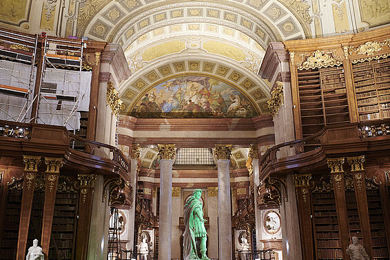 Prunkvoller Saal mit grün beleuchteter Statue in der Mitte