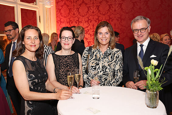 3 Frauen und 1 Herr mit Sektgläsern stehen an einem Tisch