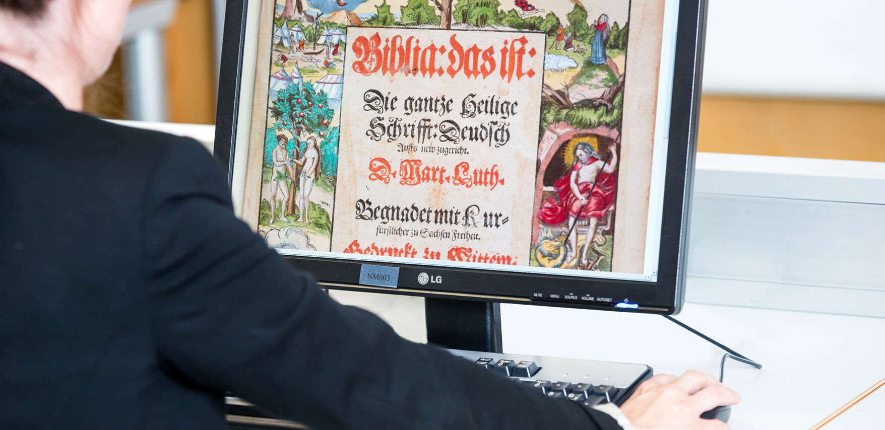 Eine Person sieht sich an einem Computer den Scan einer mittelalterlichen Handschrift an