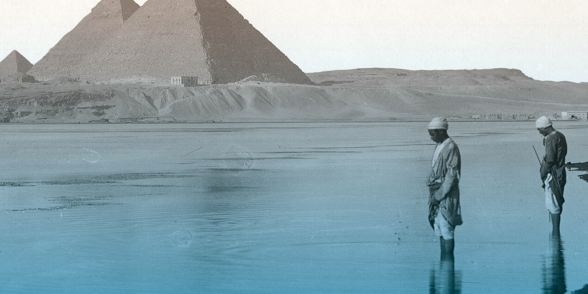 Foto von zwei Personen die im Wasser stehen, im Hintergrund Pyramiden