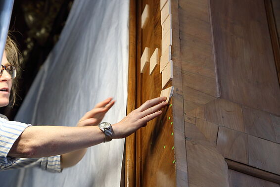Arbeiterin platziert auf die Wand quadratische Holzblätter. 