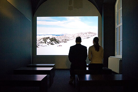 Zwei Menschen in Museumsraum mit Film auf Leinwand