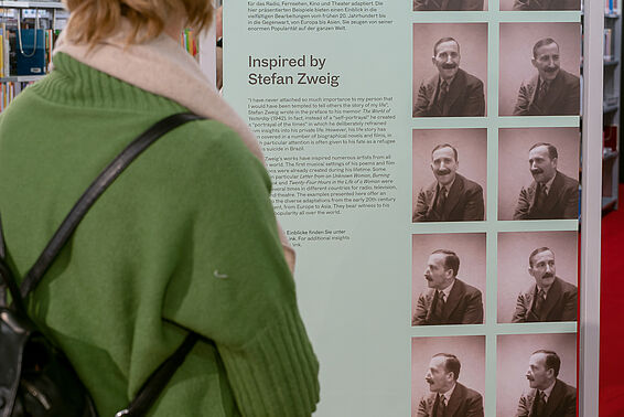 Person betrachtet einen Aufsteller mit türkiser Fläche mit Text, daneben Automatenfotos von Stefan Zweig.