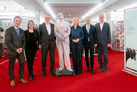 Gruppe von Menschen in Anzügen posiert mit einem Papp-Aufsteller von Stefan Zweig.
