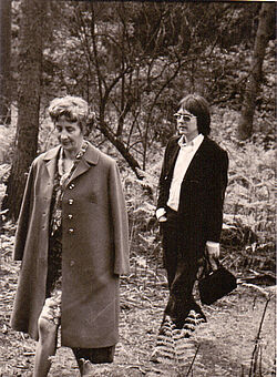 Eine Frau im Mantel und ein Mann im Anzug beim Spazieren im Wald