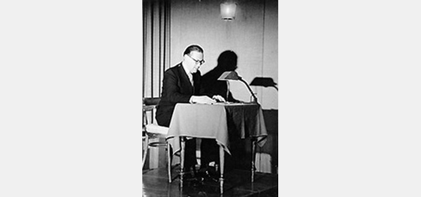 Mann sitzt an Esstisch mit kleiner Lampe, schwarz-weiß