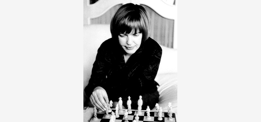 Frau auf Bett sitzend beim Schachspielen