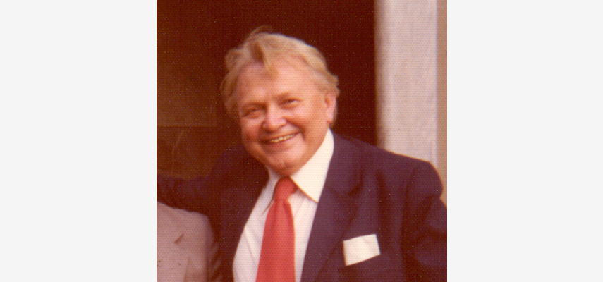 Foto von einem lächelndem Mann im Anzug mit roter Krawatte