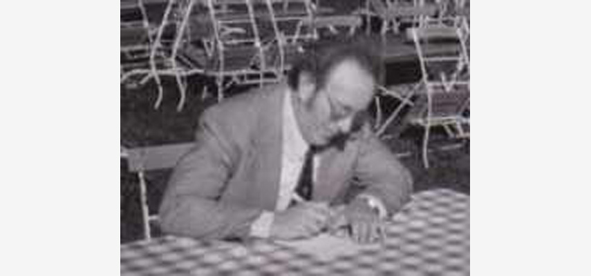 Mann an Esstisch schreibt etwas auf, schwarz-weiß