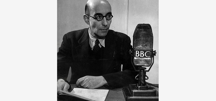 Mann mit Zetteln vor BBC-Mikrofon, schwarz-weiß