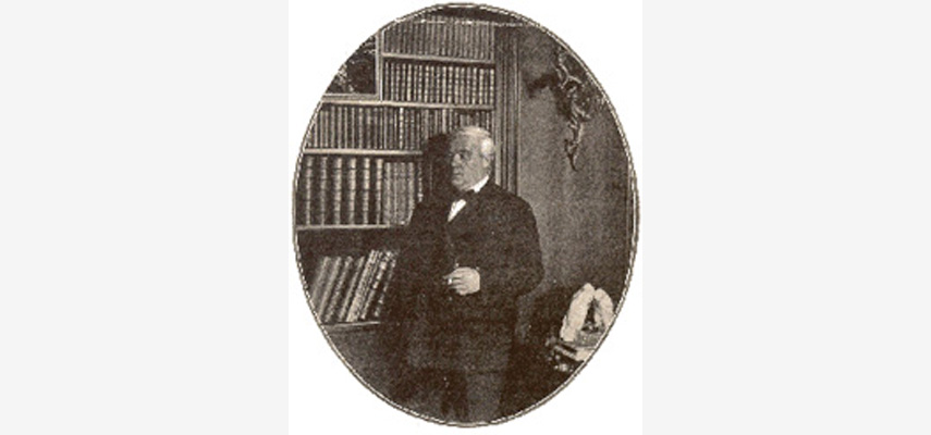 Ovales Porträt, Mann mit Fliege vor Bücherregal, schwarz-weiß