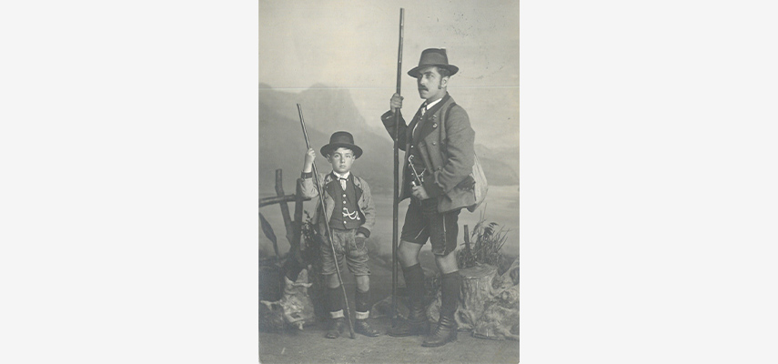 Ein Mann und ein kleiner Junge posieren in Tracht mit Gewehren.