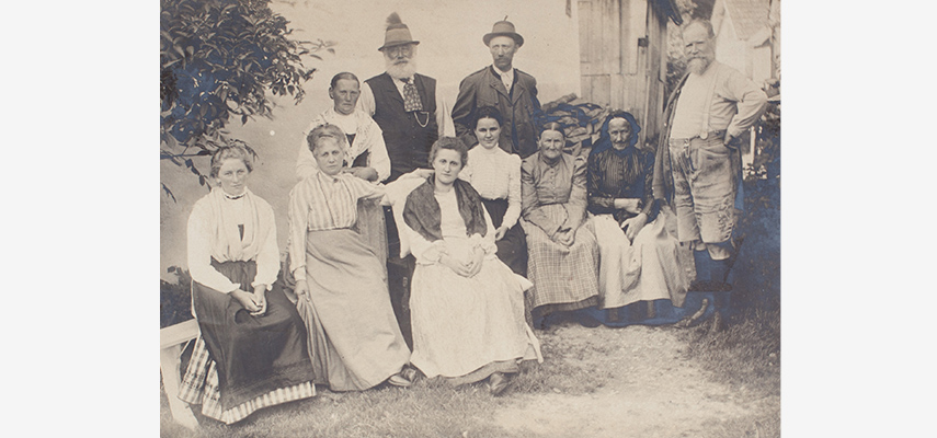 Schwarz-weißes Foto von sieben Frauen und drei Männern, die vor einem Haus posieren.