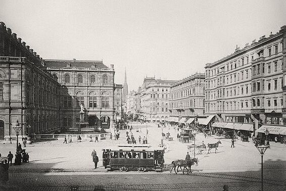 Schwarz-weißes Foto der Kärntnerstraße in Wien mit von Pferden gezogenen Straßenbahnen