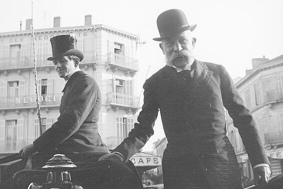 Ein älterer und ein junger Herr mit Bowler-Hüten vor Gebäuden in der Stadt, Foto, schwarz-weiß