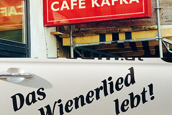 Rotes Schild "Café Kafka" und eine weiße Autotür, auf der steht "Das Wienerlied lebt!"