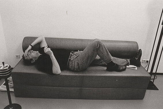 Schwarz-weißes Foto von Mann, der auf einer Couch liegt, eine Zigarette in der Hand