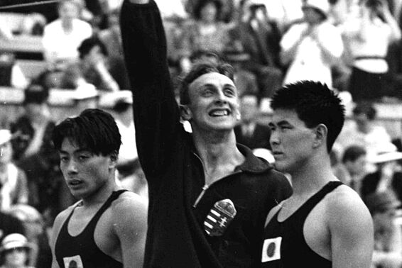 Siegerehrung der Schwimmer, der Erstplatzierte macht Hitlergruß, neben ihm stehen zwei Teilnehmer aus Japan