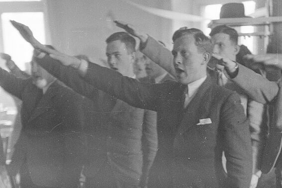 Eine Gruppe von Männern macht den Hitlergruß in einem Lokal