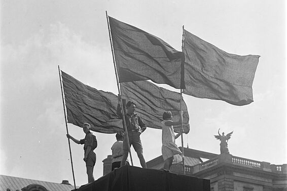 Vier Jugendliche mit Fahnen auf einem Podest auf dem Wiener Heldenplatz
