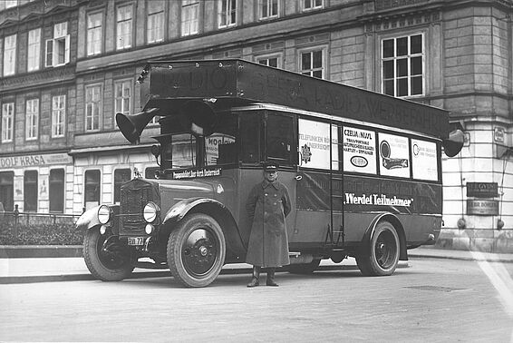 Mann vor einem alten Autobus mit Werbung darauf