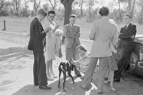 Elegant gekleidete Personen mit Hund in der Mitte