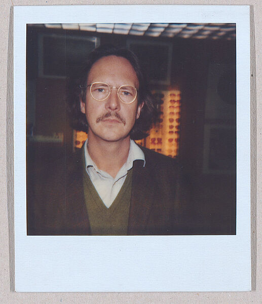 Polaroid-Foto von Mann mit Schnauzer und Brille bei einem Optiker