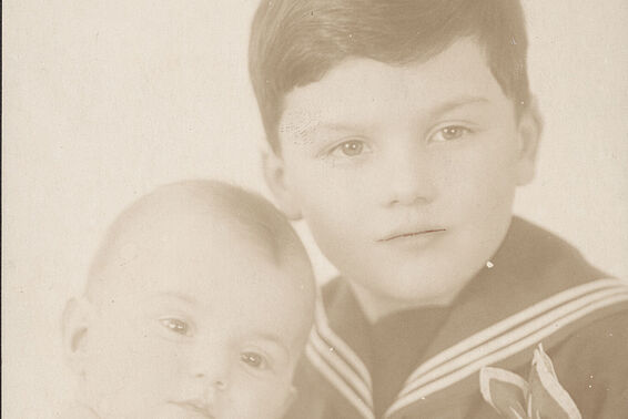 Vergilbtes, altes Foto von einem Jungen in Uniform und einem Baby.